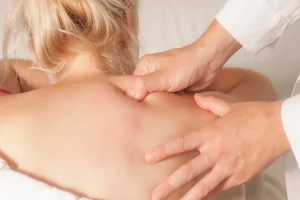 Woman lying on massage table in quiet room with candles and soft lighting