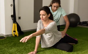 Athlete lying face down receiving focused muscular massage on upper back after workout