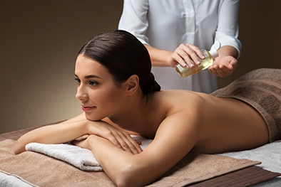 Closeup of therapist massaging client’s neck beside folded white towels