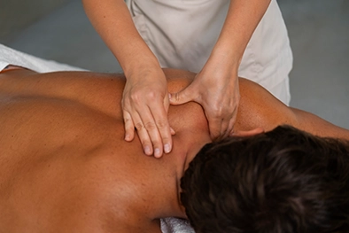 Smooth hot stones arranged along client’s spine on a white sheet
