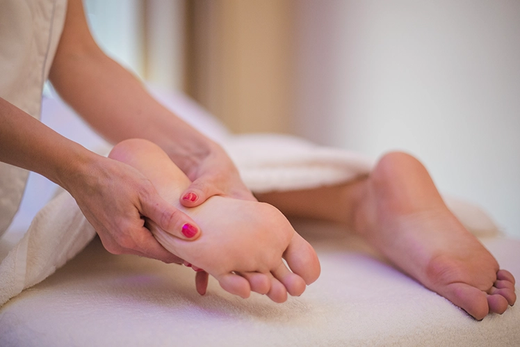 Close-up of practitioner pressing specific points on the sole of a foot