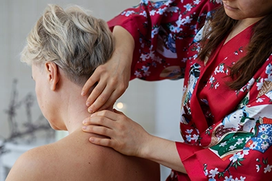 Massage therapist applying focused thumb pressure to a client’s upper back